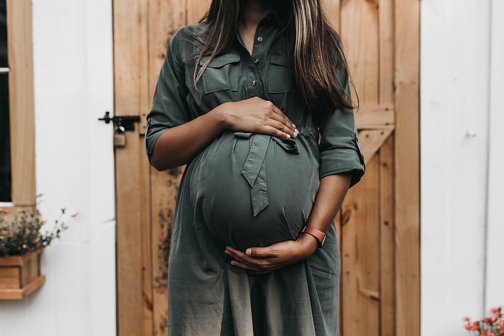 Eine schwangere Frau hält ihren Bauch